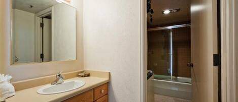 A bathroom with a sink, mirror, and shower.