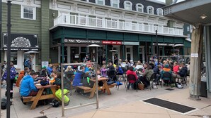 A crowded outdoor dining area with wooden tables and benches, a balcony, and a sign indicating "No Smoking." - Lodge at Mountain Village by Park City Vacations (Park City)