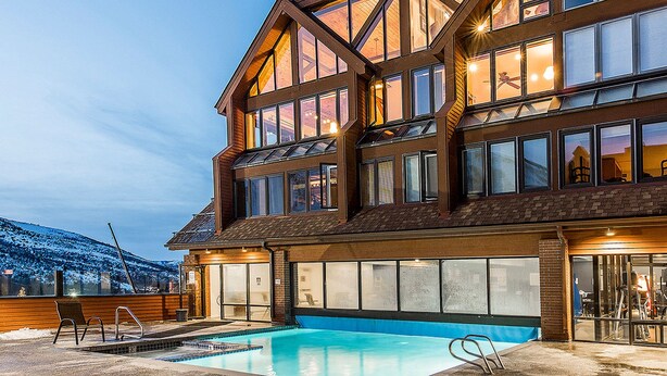 A large, multi-story building with a swimming pool in the foreground. - Lodge at Mountain Village by Park City Vacations (Park City)