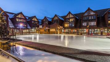 A hotel with a central ice rink, multiple buildings with large windows, and outdoor seating areas.