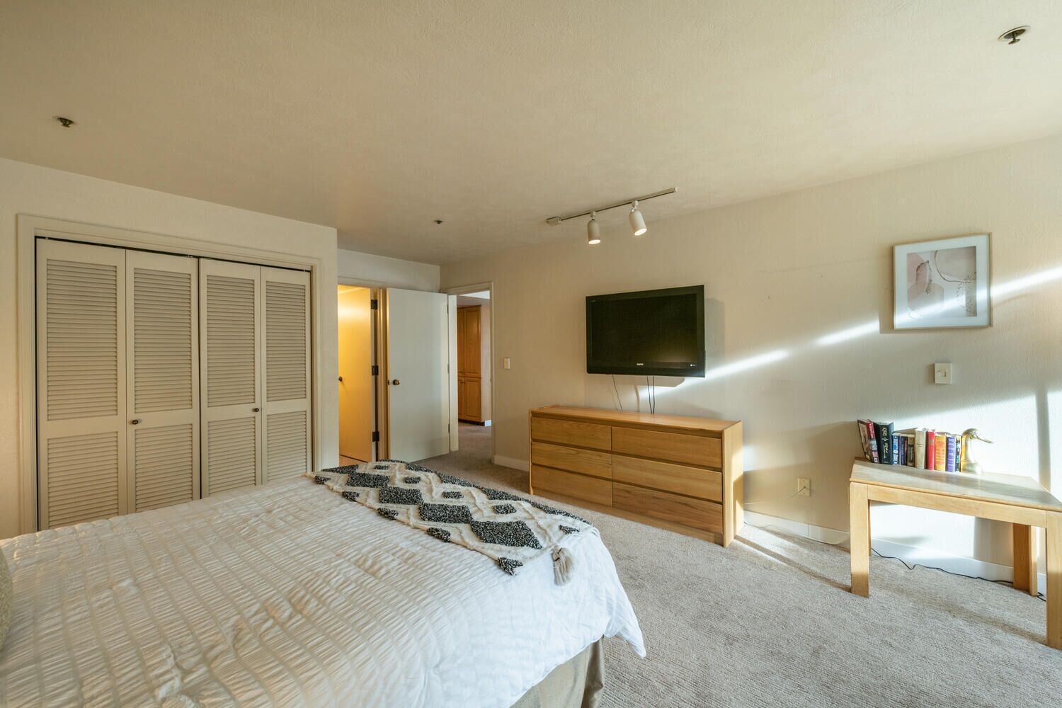 A bedroom with a bed, a dresser, a TV, and a bookshelf.