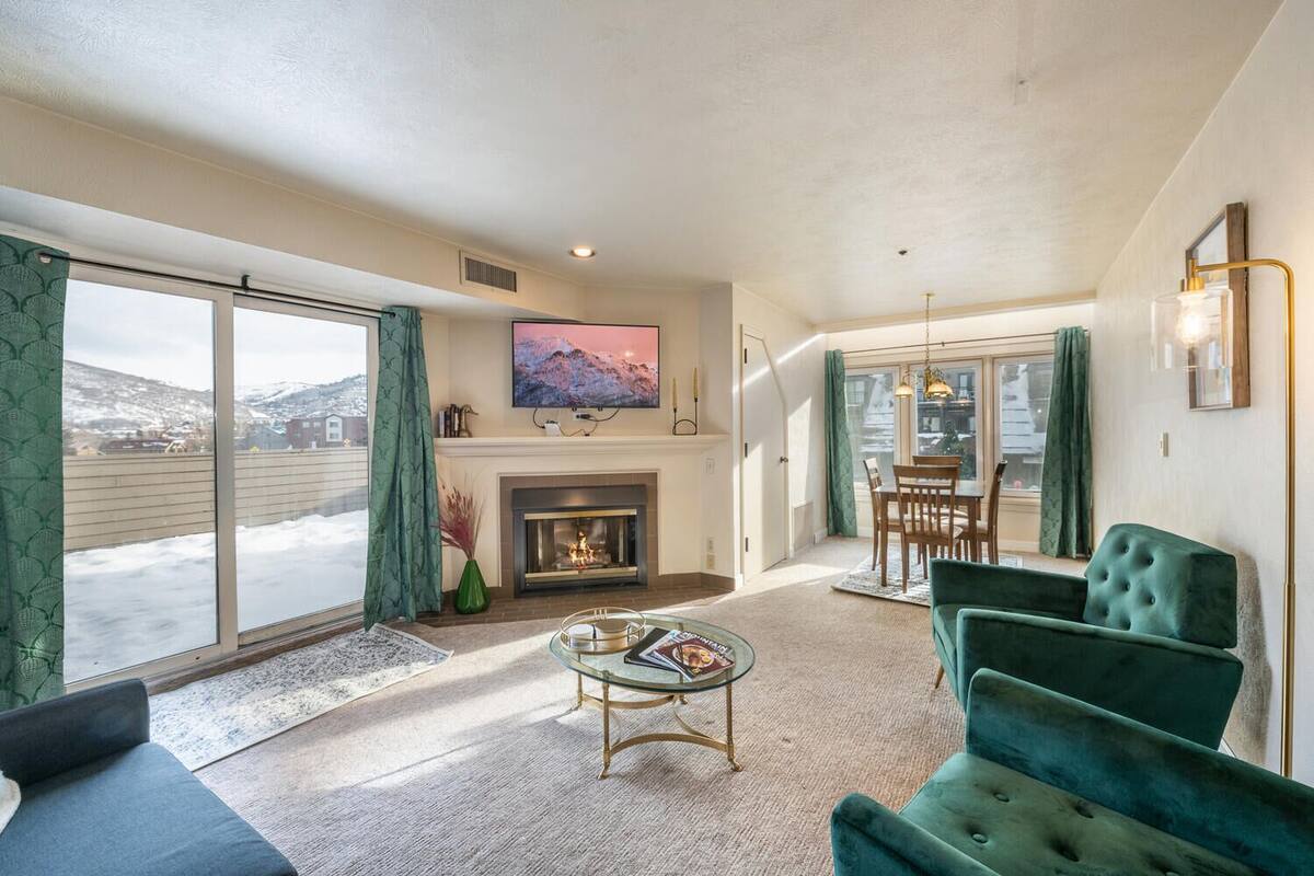 A spacious living room with a fireplace, a television mounted above it, and a dining area with a table and chairs.