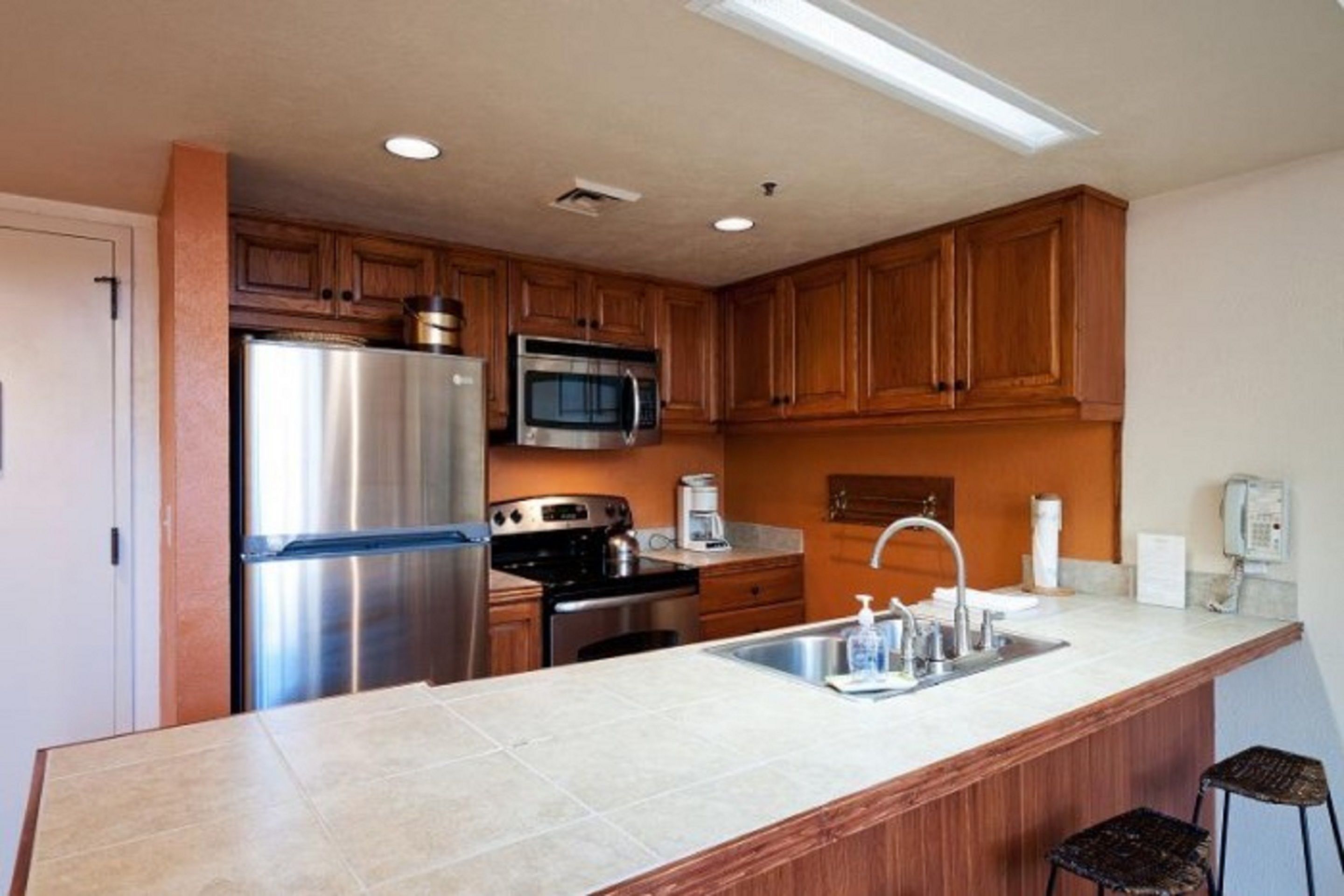 A modern kitchen with wooden cabinets, stainless steel appliances, and a large island with a sink.