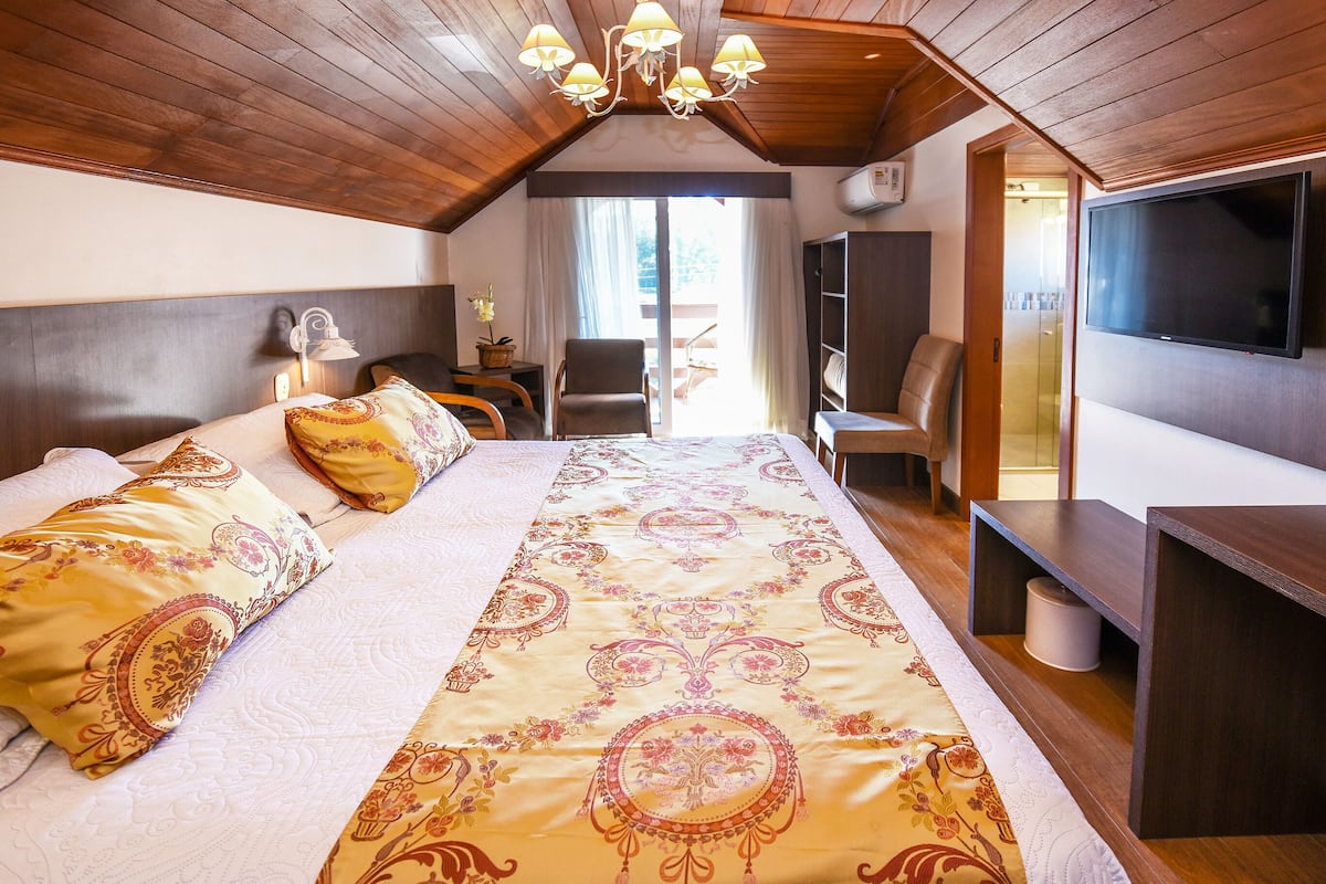 Ein Schlafzimmer mit einem großen Bett, einem Fernseher, einem Schreibtisch und einem Stuhl.
