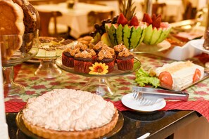 A buffet table with various desserts including a large pie, cupcakes, and a watermelon slice. - Hotel Kehl Haus (Gramado)