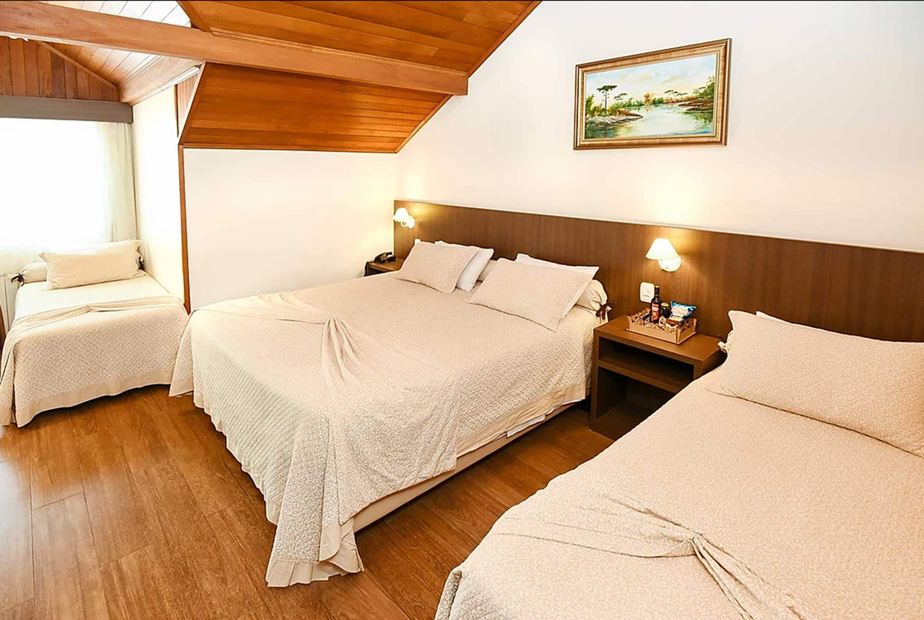 Una habitación de hotel con dos camas, suelo de madera, un cuadro en la pared y lámparas de noche.