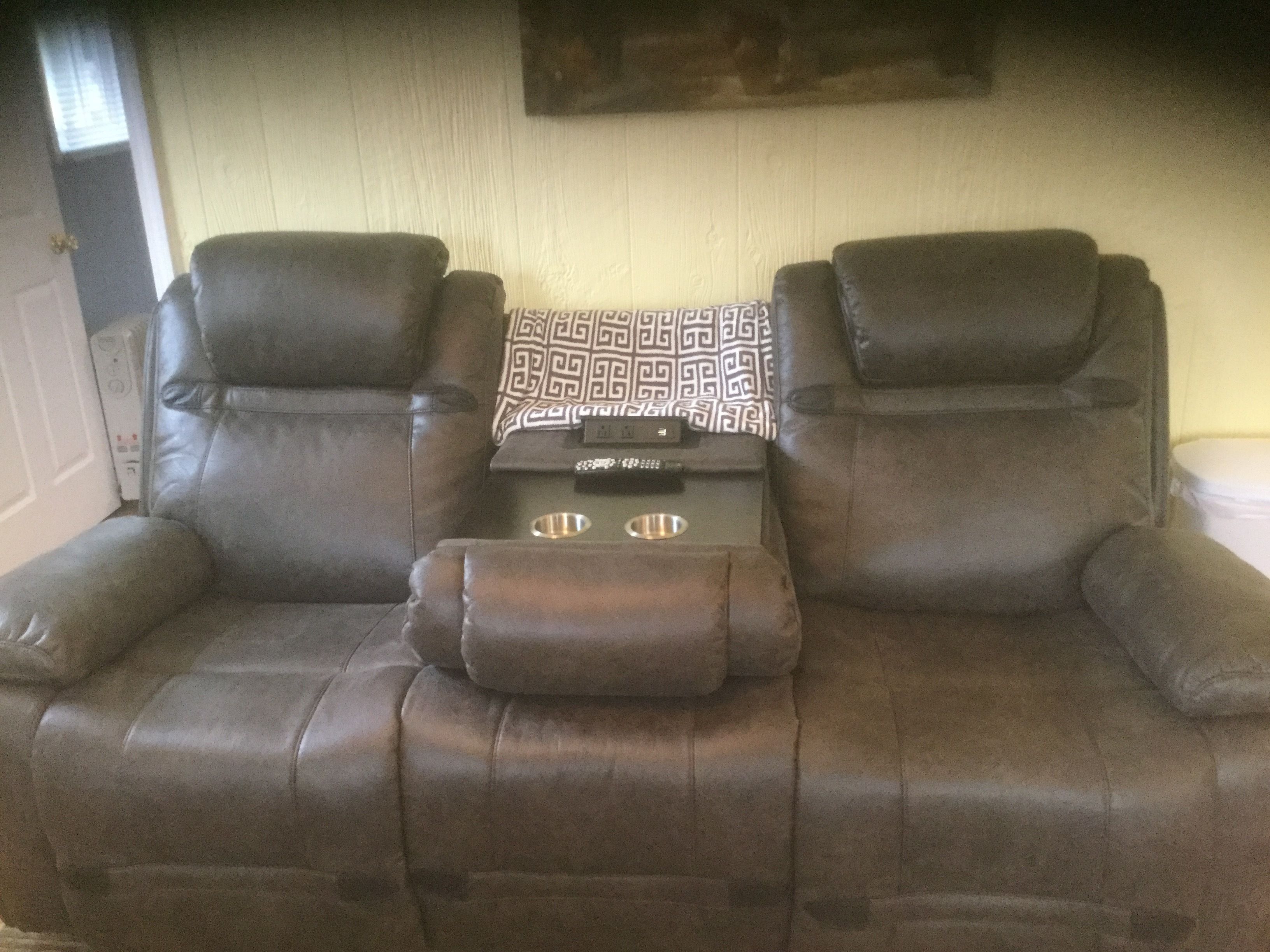 A brown leather sofa with a patterned throw pillow and a remote control on it.
