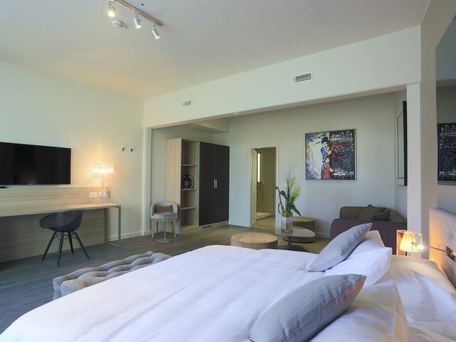 Une chambre d’hôtel moderne avec un grand lit, un bureau avec une chaise, une télévision et un tableau au mur.