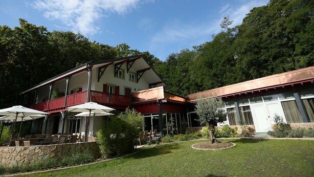 A two-story building with a balcony, outdoor seating area, and a well-maintained garden. - Chez Maman (Geneva)