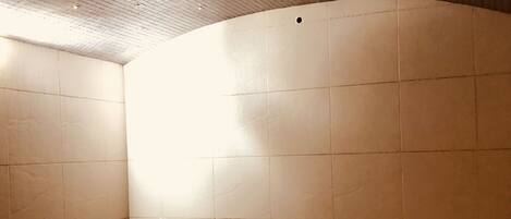 Un angolo di stanza con una parete piastrellata, una fascia di mosaico e un soffitto con faretti.