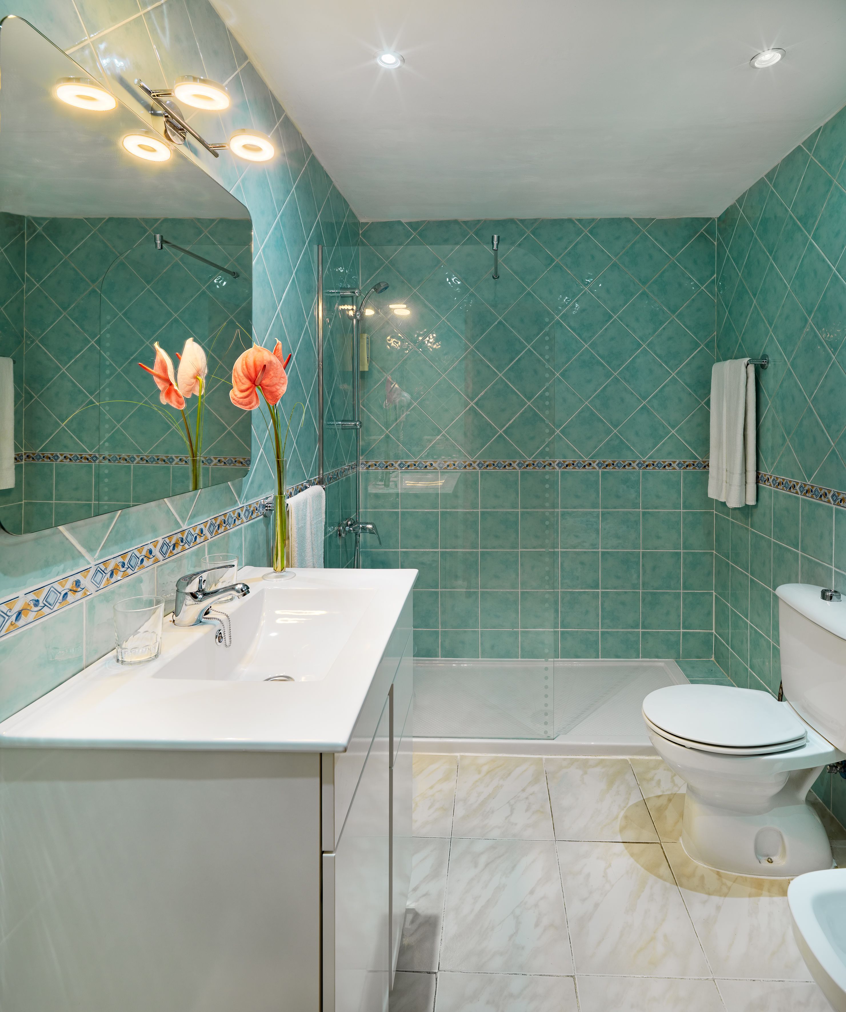 A bathroom with a white sink, mirror, and toilet.