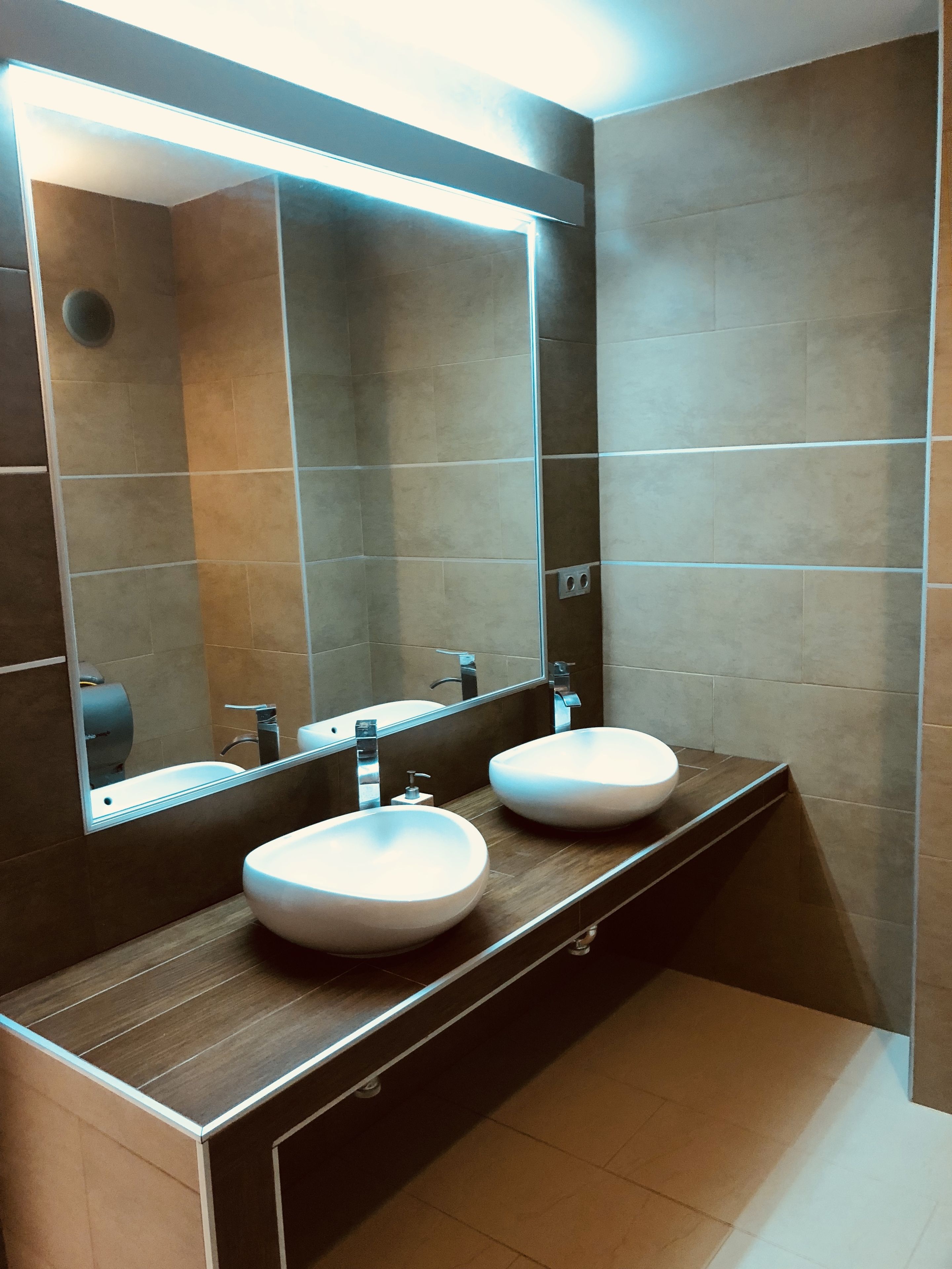 Une salle de bain moderne avec deux lavabos, un grand miroir et une douche.