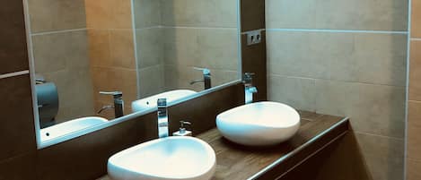 Une salle de bain moderne avec deux lavabos, un grand miroir et une douche.