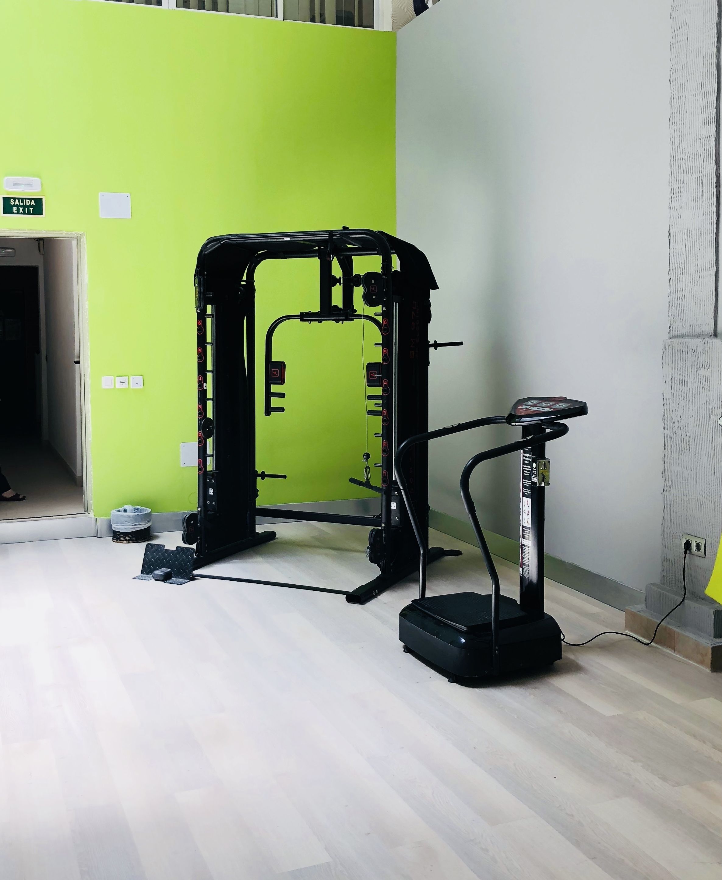 Een sportschool met een gewichthefstation en een hometrainer.