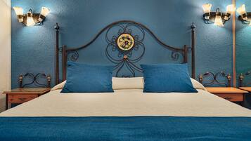 Una cama con cabecera, dos almohadas y dos mesitas de noche con lámparas.