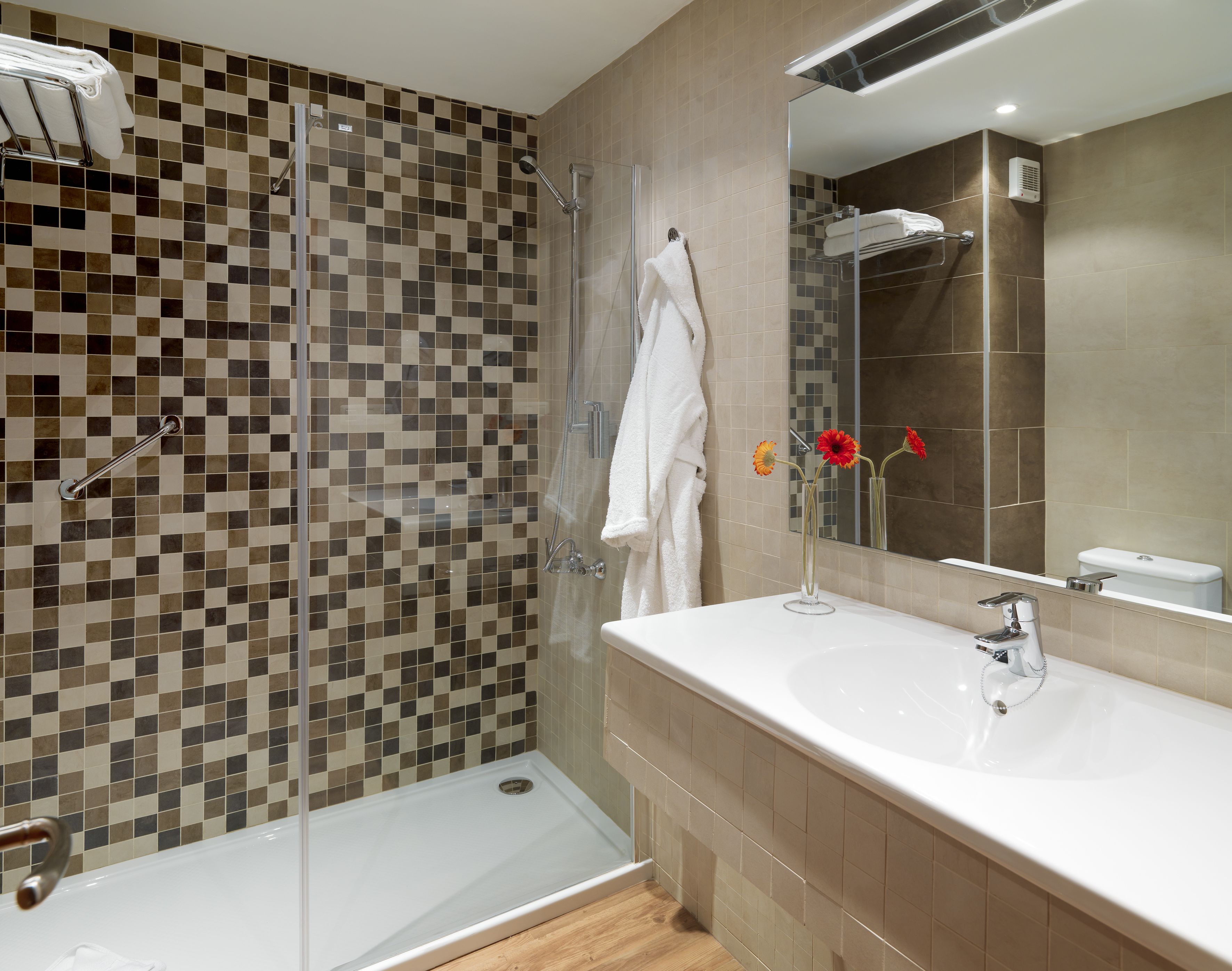 A modern bathroom with a glass-enclosed shower, a white sink, and a mirror above it.