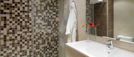 A modern bathroom with a glass-enclosed shower, a white sink, and a mirror above it.