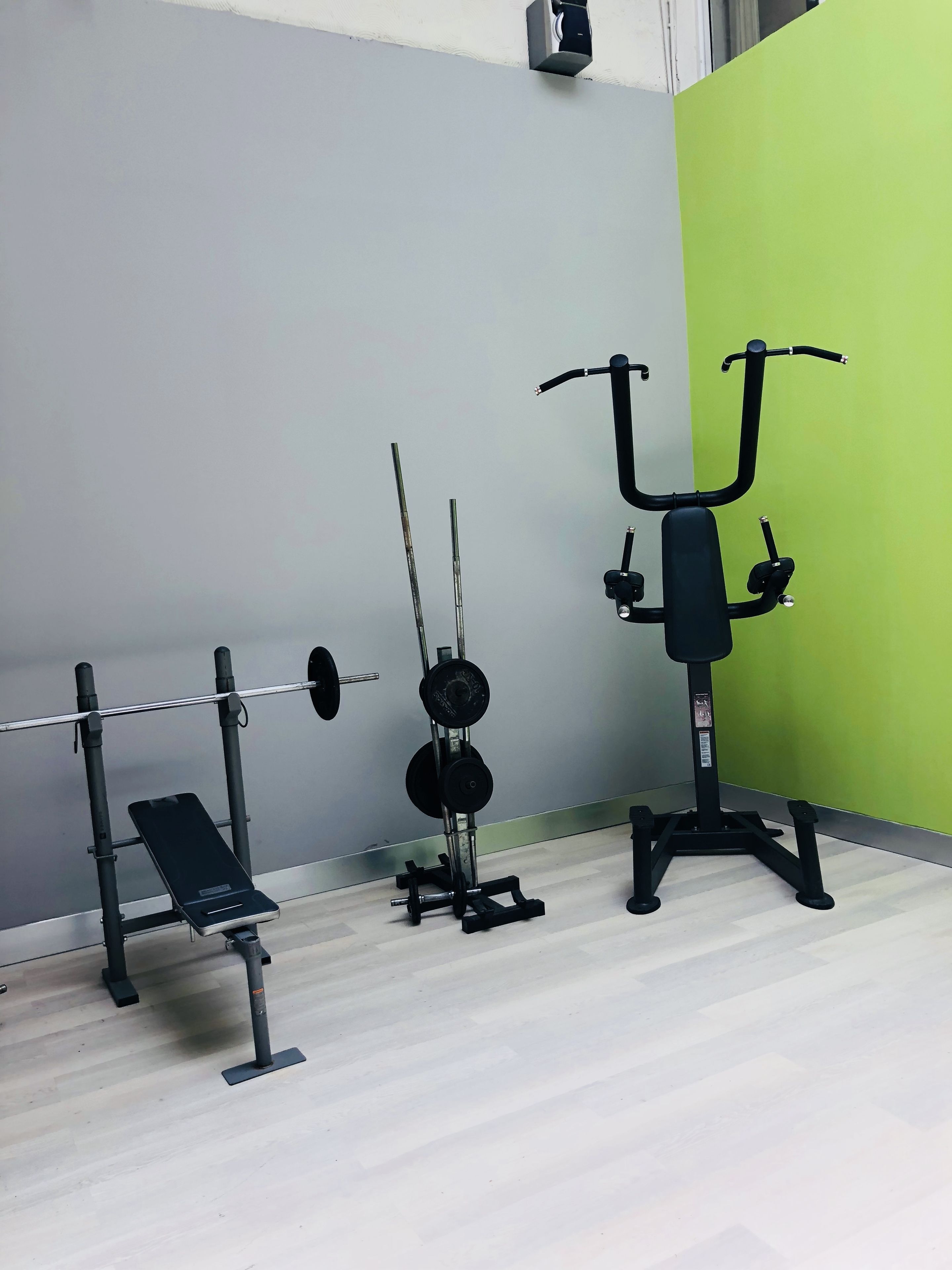 Une salle de sport équipée d’un banc de développé couché, d’un support à squats et d’une machine à câbles.