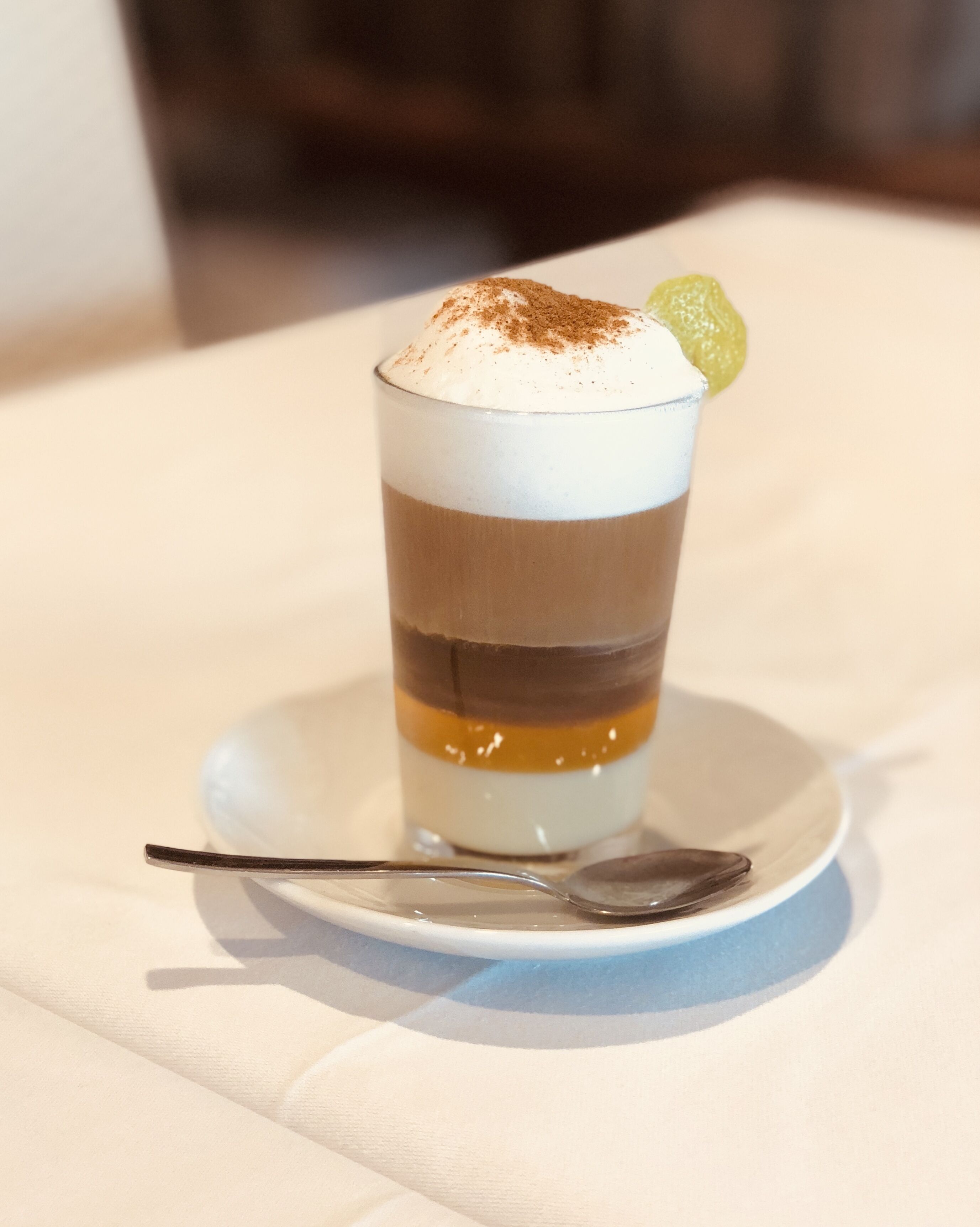 Un dessert composé de plusieurs couches, présenté sur une assiette blanche avec une cuillère.