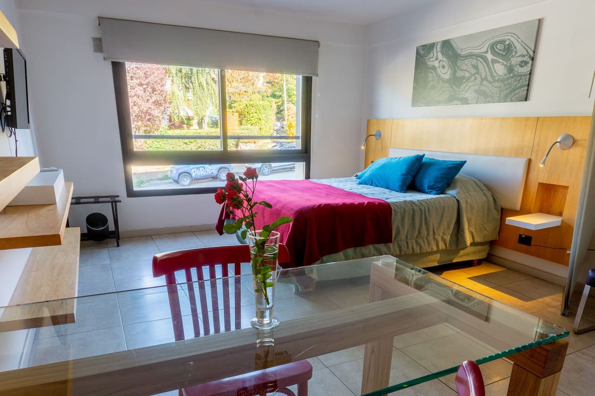 Une chambre à coucher moderne, avec un lit, une table de chevet et une fenêtre donnant sur l’extérieur.