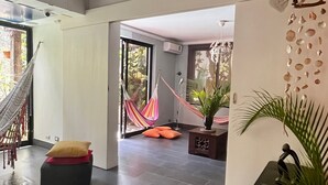 A spacious living area with a hammock, a potted plant, and a staircase.