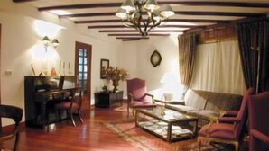 A cozy living room with a wooden ceiling, a chandelier, a sofa, and a coffee table. - Pazo Carrasqueira (Ribadumia)