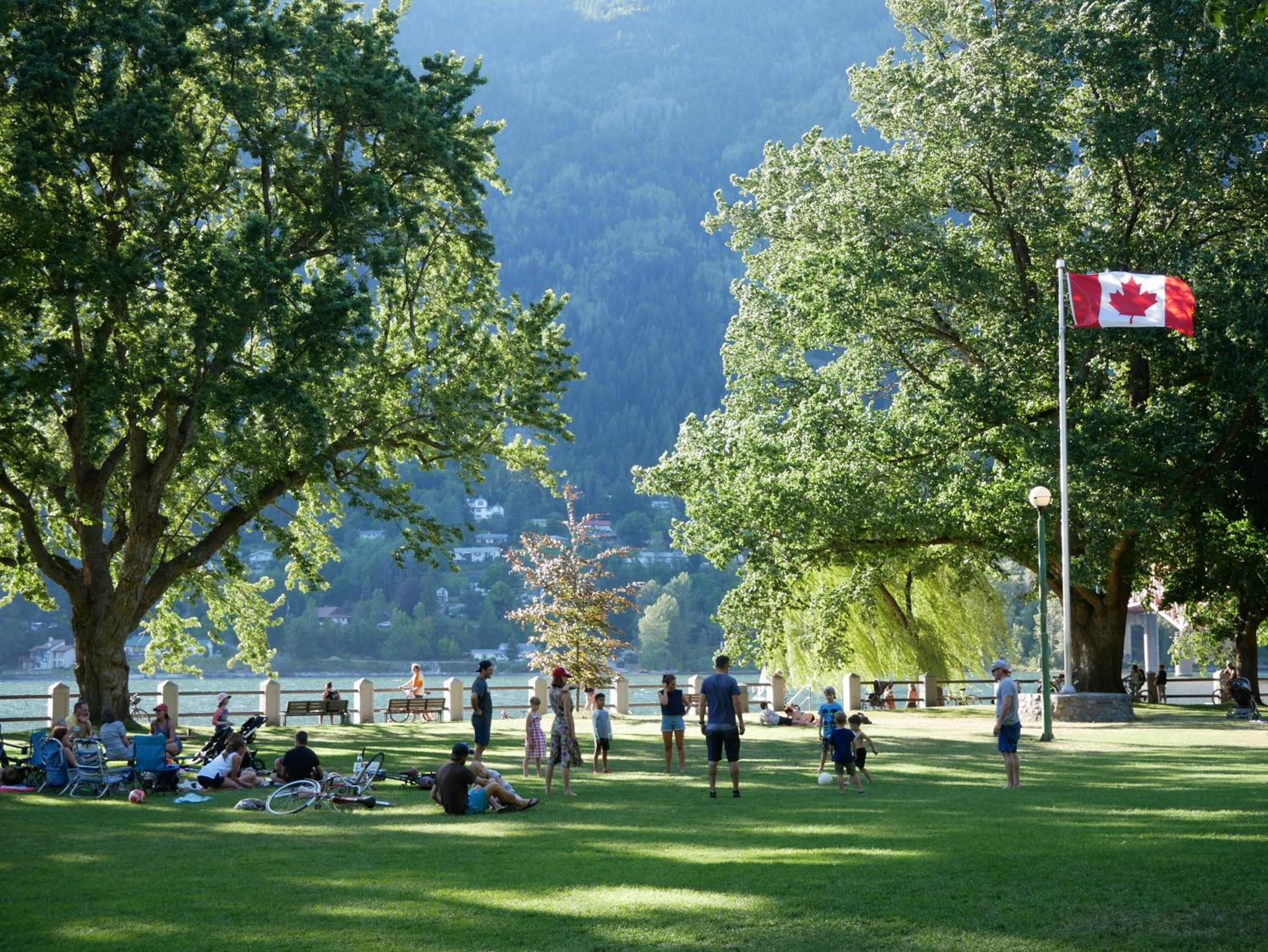 Un parque con una bandera, árboles y gente.