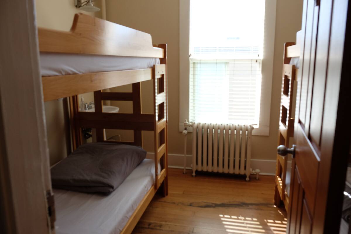 A bunk bed room with a window and radiator.