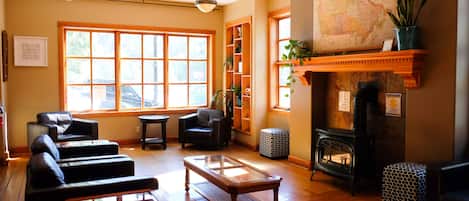 A cozy living room with leather sofas, a glass-top coffee table, a fireplace, and a large window with a view.