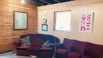 A room with a wooden wall, a red sofa, and a window.