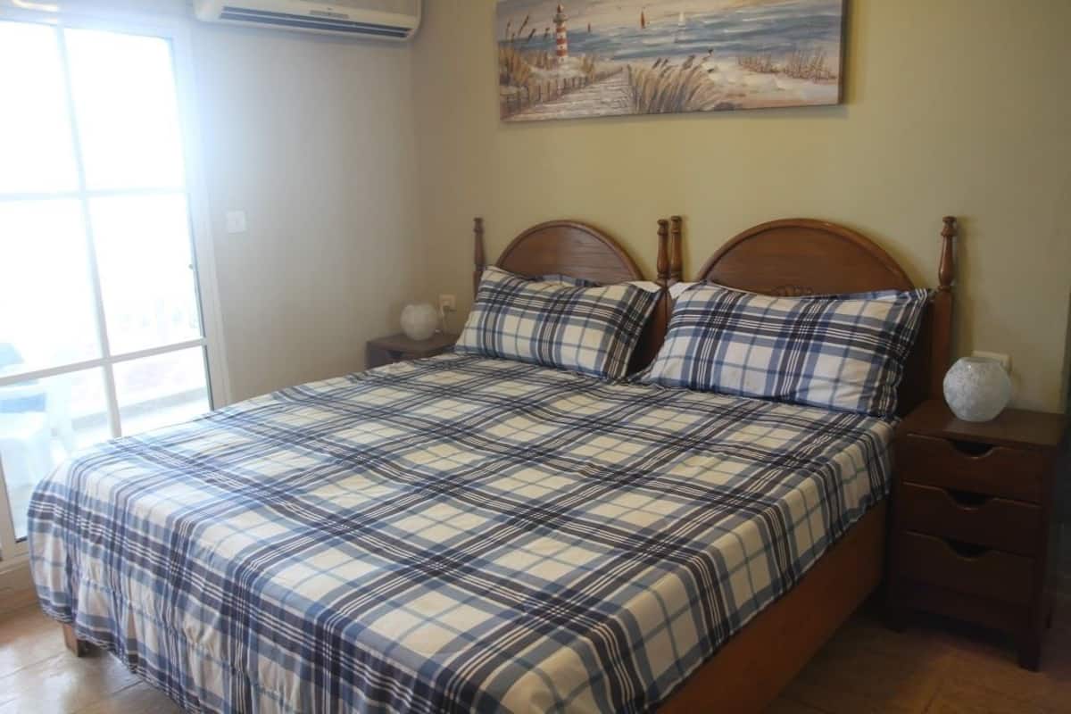 Quarto com uma cama grande, duas mesas de cabeceira, uma janela e um quadro na parede.