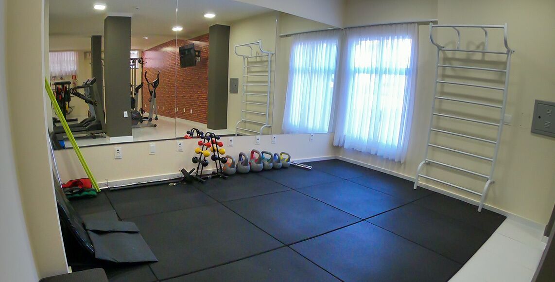Un gimnasio con equipo de ejercicio, un espejo y una ventana con cortinas.