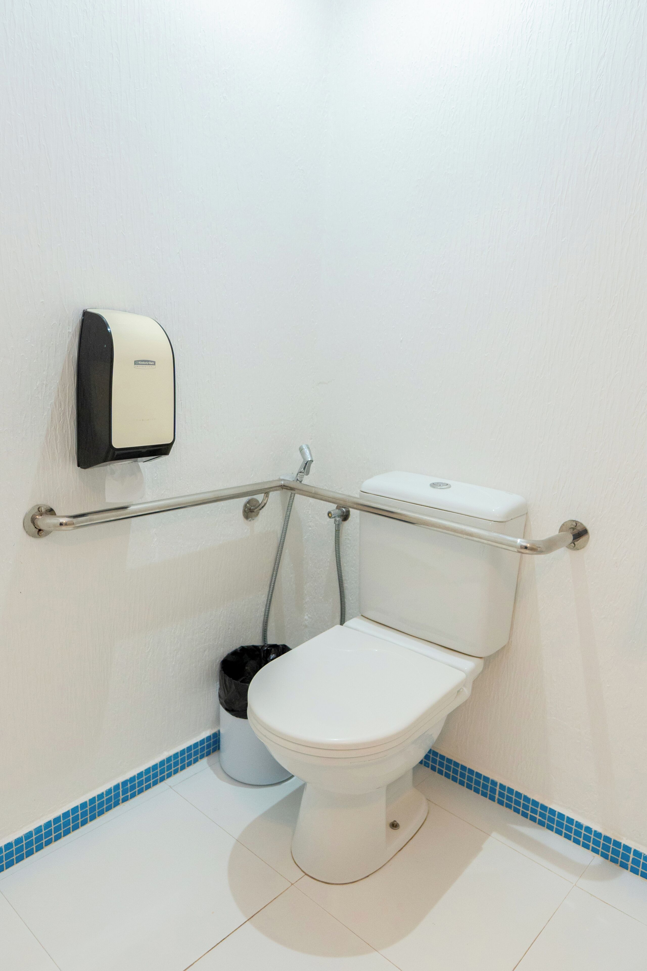 Un water bianco con un dispenser di gel disinfettante a parete.