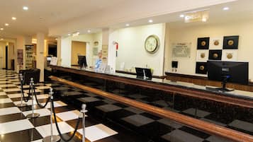 A hotel reception area with a check-in counter, a clock, and a sign indicating the check-in location.