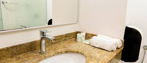 Une salle de bain avec un comptoir en granit, un lavabo blanc, un miroir et un porte-serviettes.