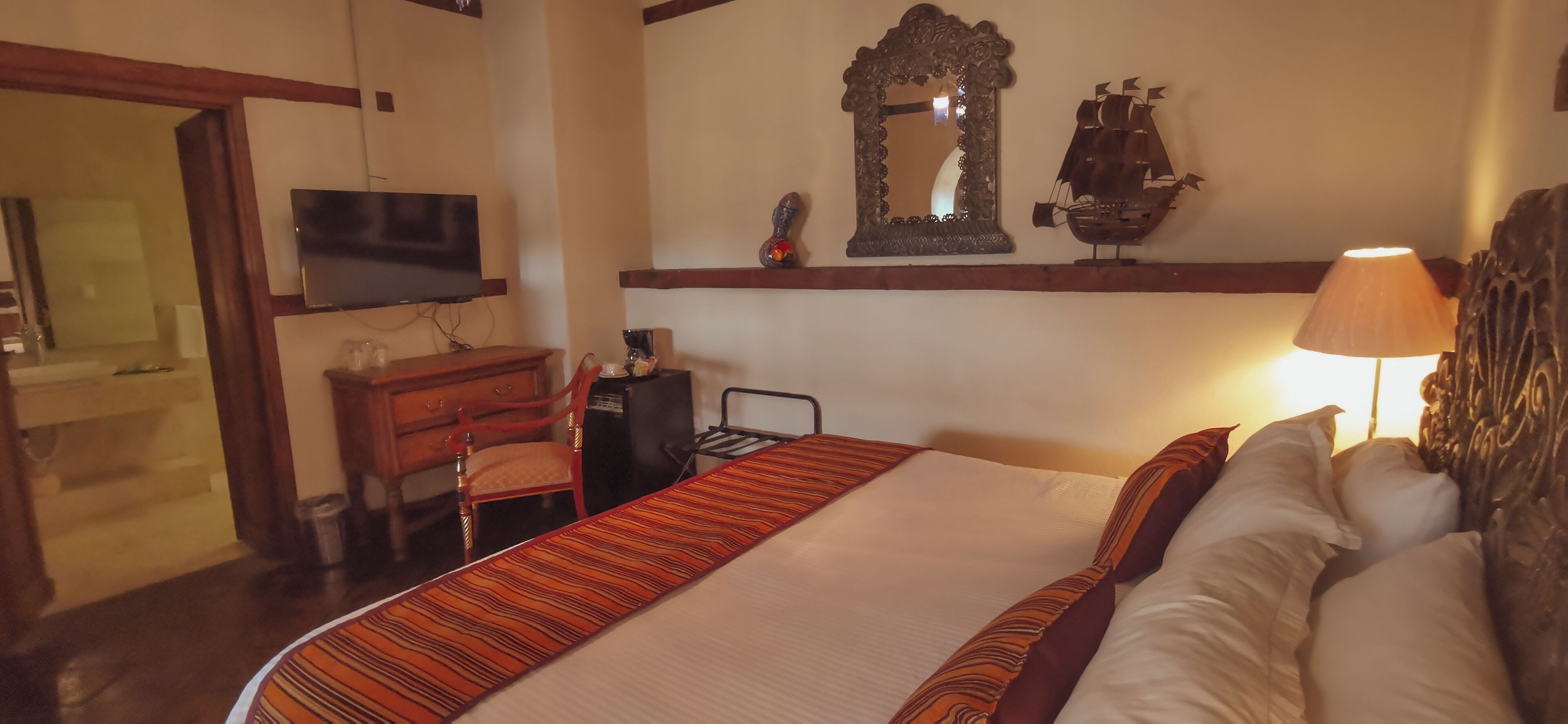 Una habitación de hotel con cama, televisión, escritorio y espejo.