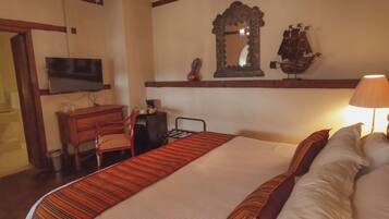Una habitación de hotel con cama, televisión, escritorio y espejo.