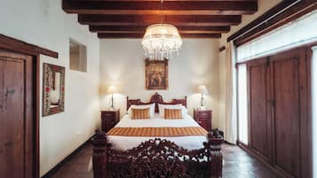 Una habitación tradicional con una cama de madera, un candelabro y un espejo grande.