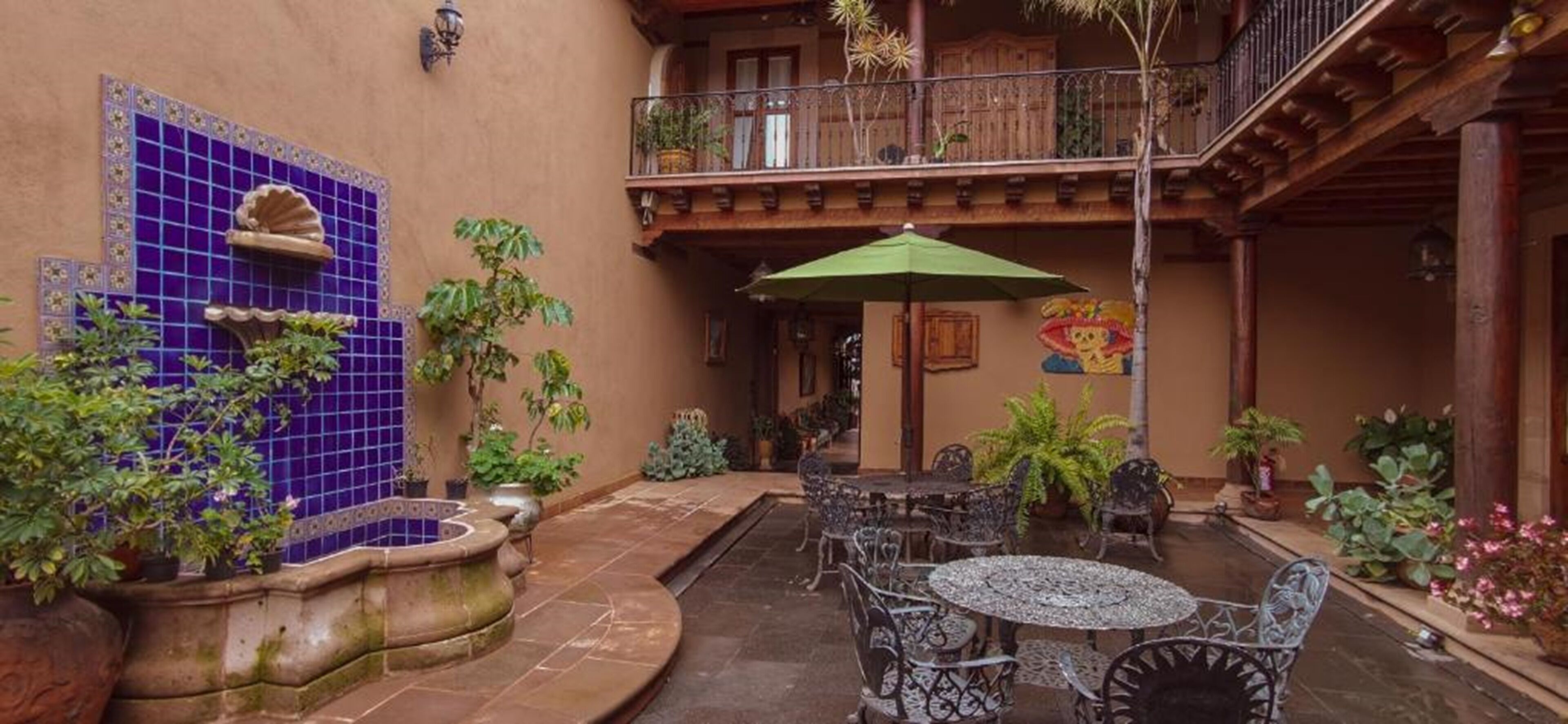 Un patio con pared de azulejos azules, una fuente y mobiliario para exterior.
