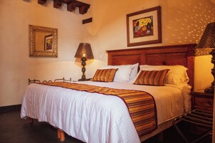 Una cama bien hecha con ropa de cama a rayas, un cabecero de madera, una lámpara de noche y un cuadro en la pared.