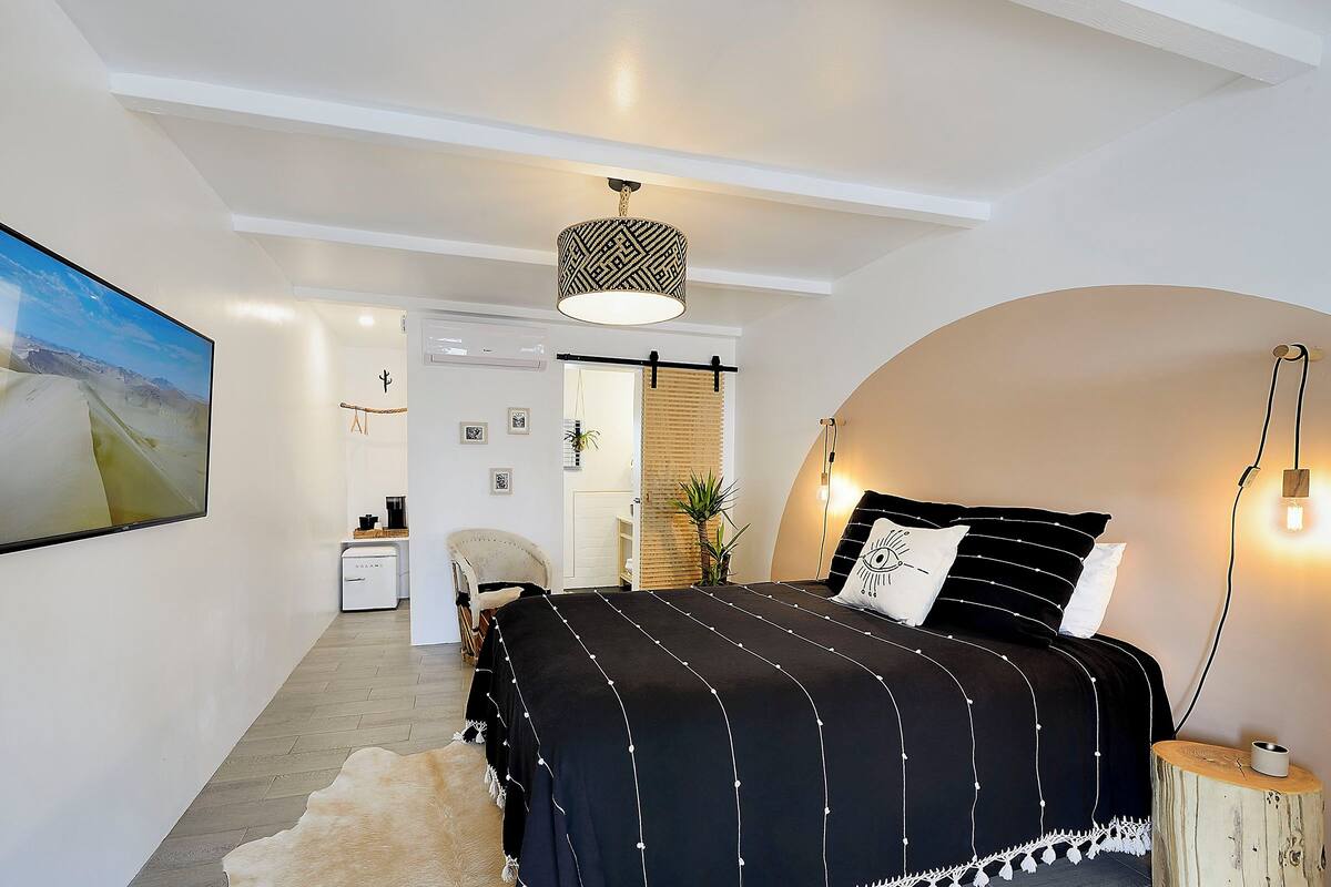 Une chambre à coucher avec un lit, un luminaire suspendu et un tableau au mur.