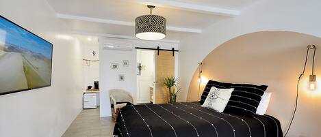 A bedroom with a bed, a hanging light fixture, and a painting on the wall.
