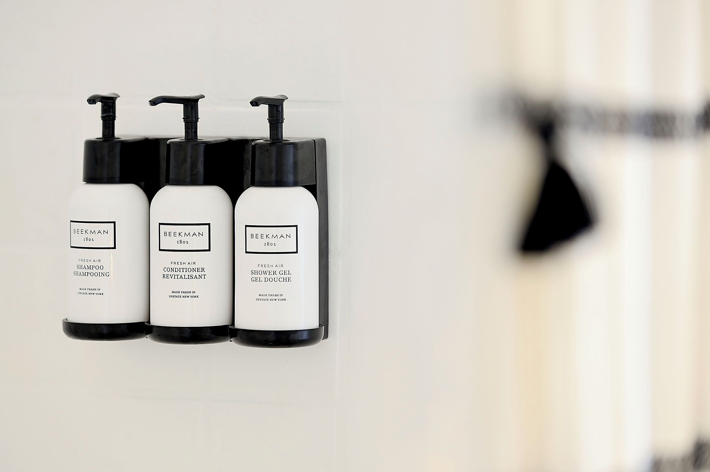 Três produtos Beekman Fresh Air expostos numa parede: shampoo, condicionador e gel de banho.
