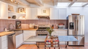 A modern kitchen with white cabinetry, a stainless steel refrigerator, a gas stove, and a tiled floor. - The Mystic Santa Fe (Santa Fe)