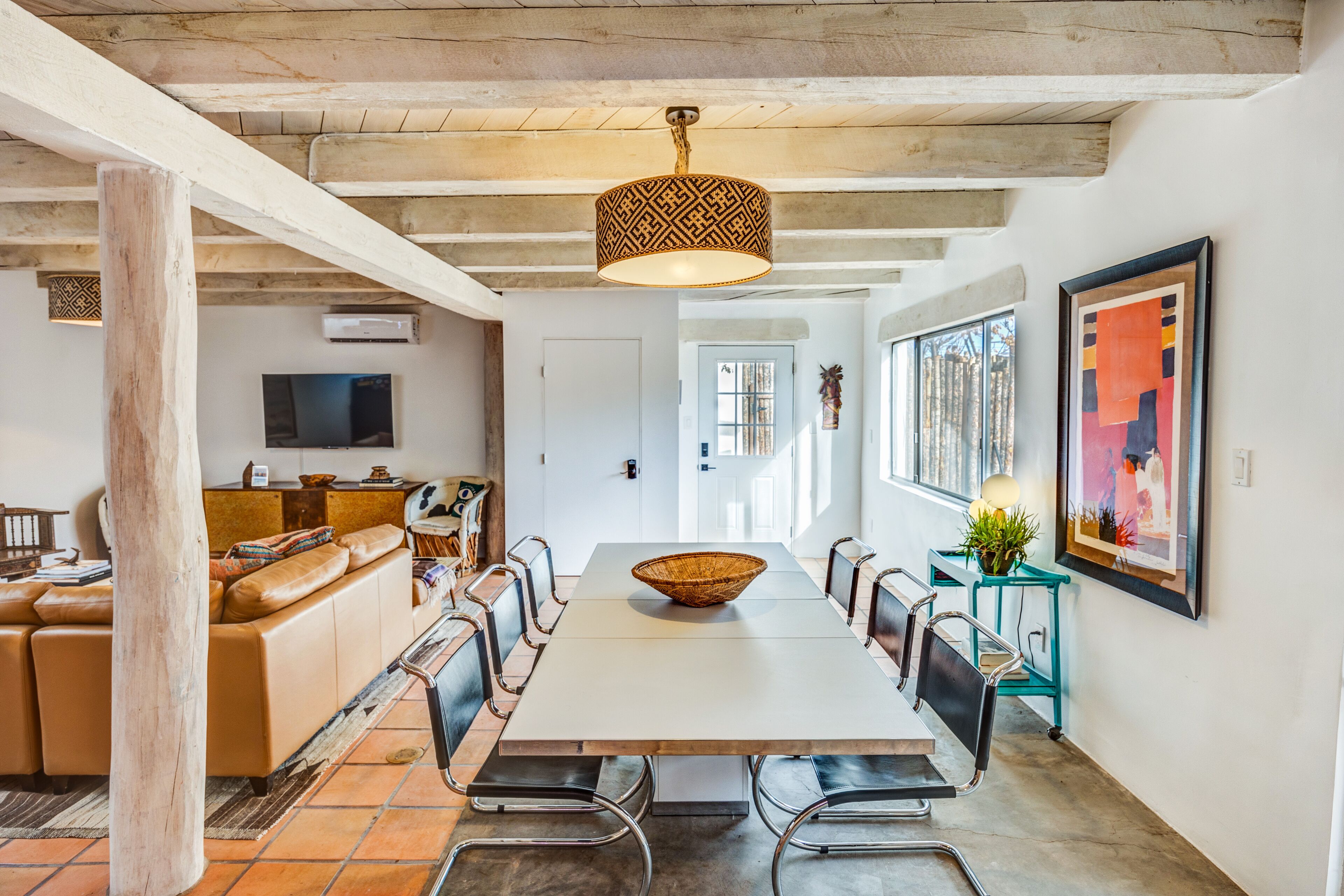 A spacious dining area with a long table, modern chairs, and a hanging light fixture.