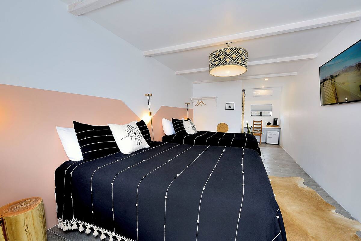 Une chambre à coucher moderne avec un grand lit, une lampe suspendue et un tableau au mur.