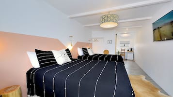 Un dormitorio moderno con una cama grande, una lámpara colgante y un cuadro en la pared.