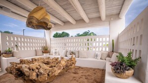A modern outdoor seating area with a rustic wooden coffee table, white cushioned sofas, and potted plants. - The Mystic Santa Fe (Santa Fe)