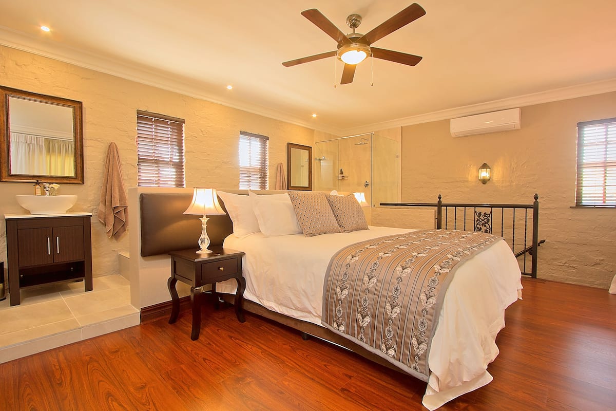 A bedroom with a bed, bedside table, lamp, and a ceiling fan.