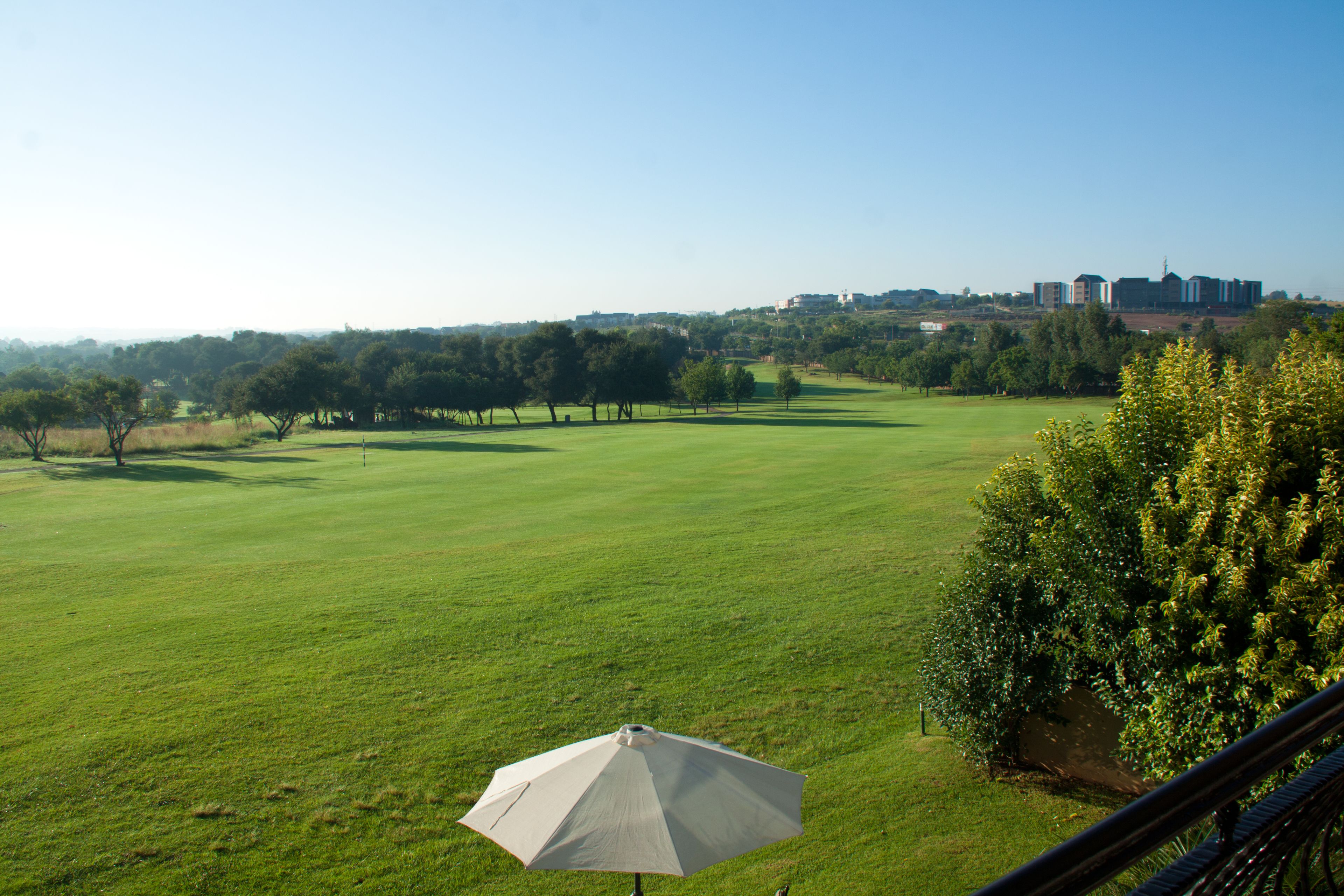 Vista de un campo de golf con un paraguas grande al frente.